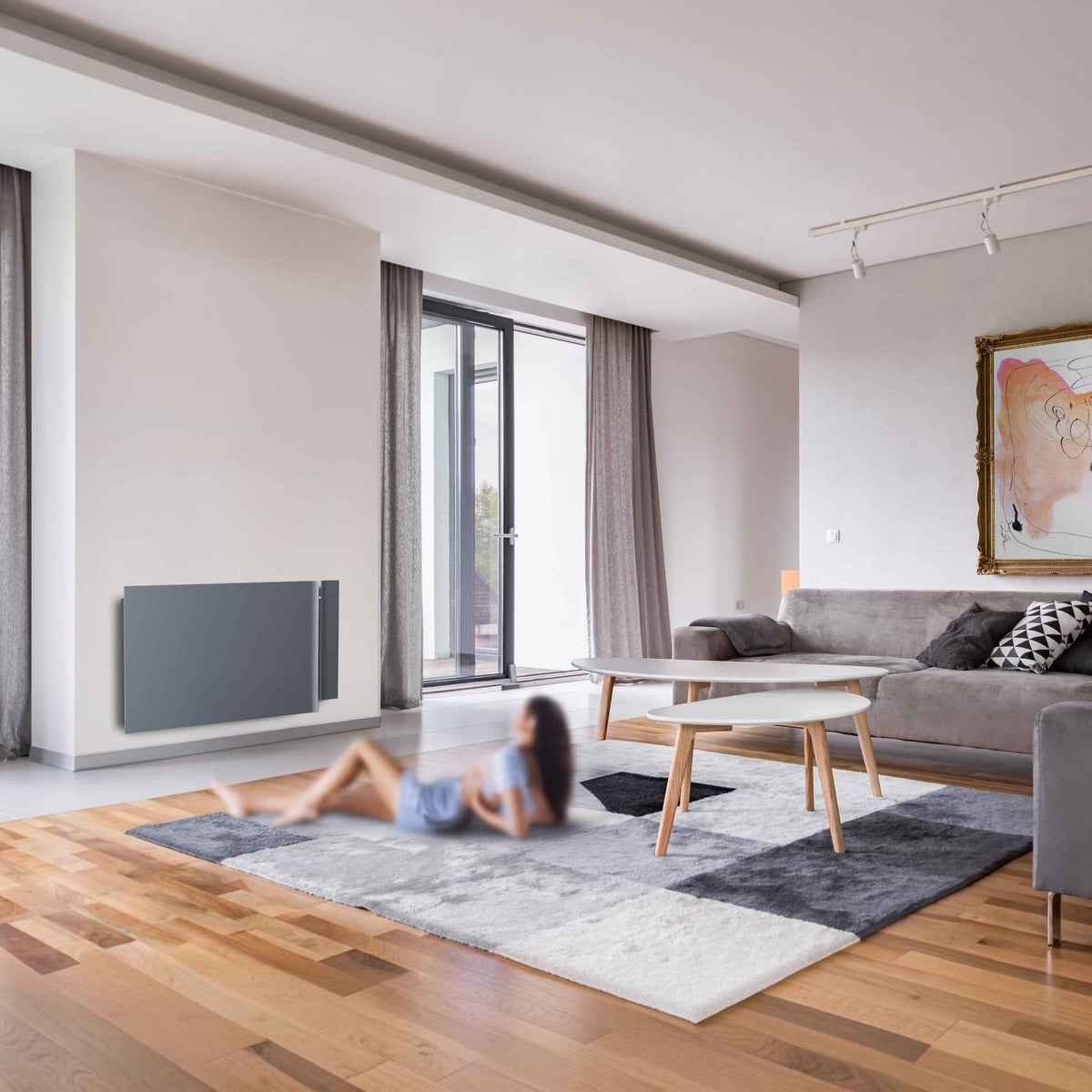 Radiatore elettrico da parete Klimago™ Radialight KYOTO grigio antracite in un moderno soggiorno con donna rilassata