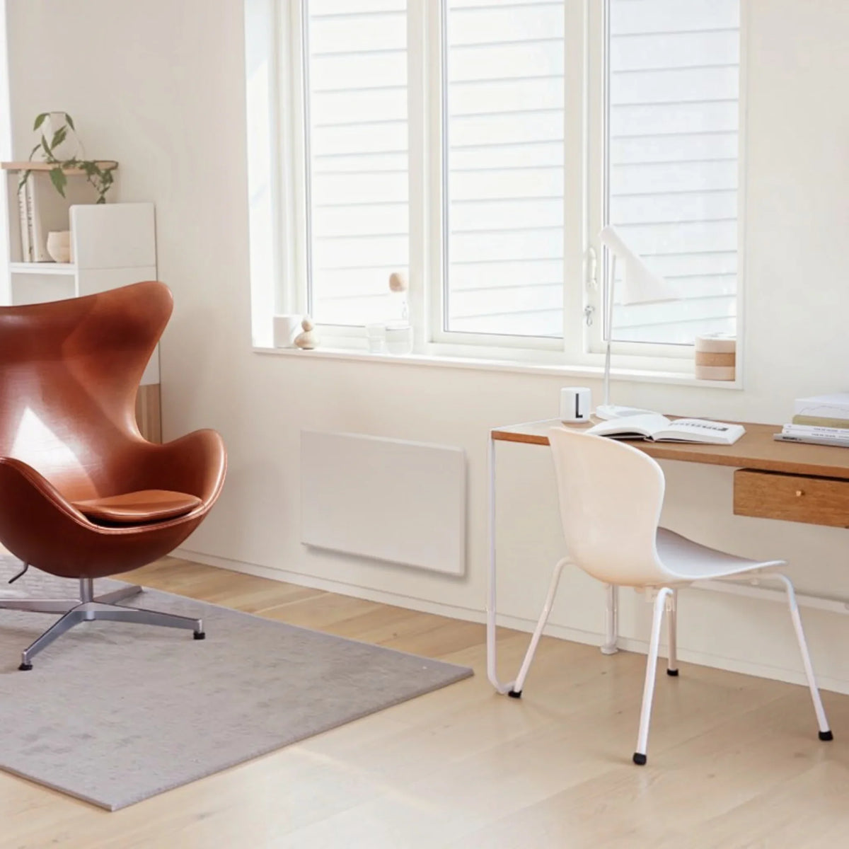 Radiatore elettrico norvegese Klimago™ NOBO TOP bianco installato a parete in un moderno soggiorno luminoso