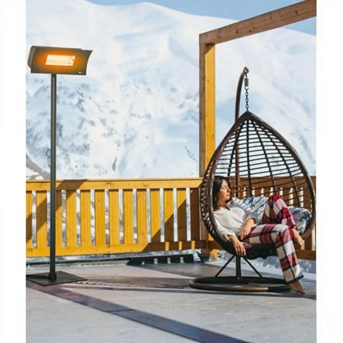 Riscaldatore a infrarossi esterno Klimago Radialight OASI HT nero su piantana in un terrazzo innevato con poltrona