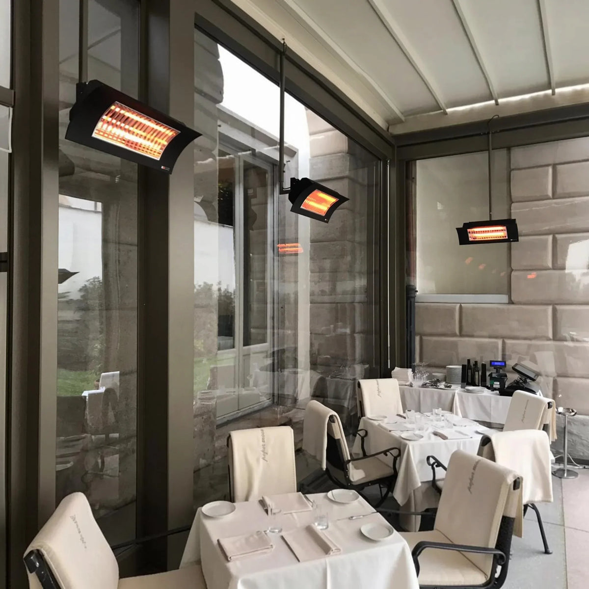 Riscaldatori a infrarossi Radialight OASI Low Glare installati a soffitto in una veranda esterna Klimago