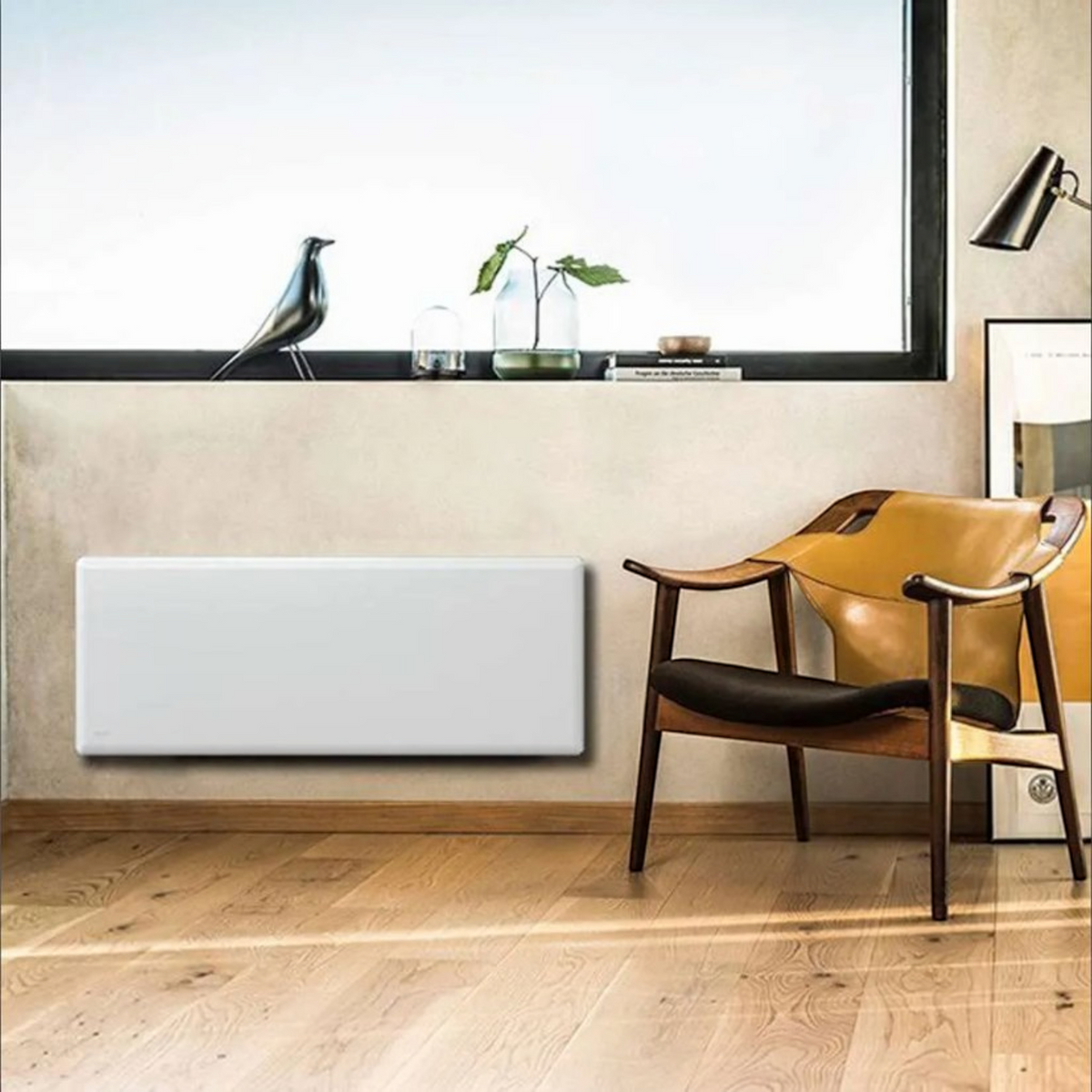 Radiatore elettrico a convezione Klimago™ NOBO TOP bianco installato a parete in un soggiorno moderno e luminoso.