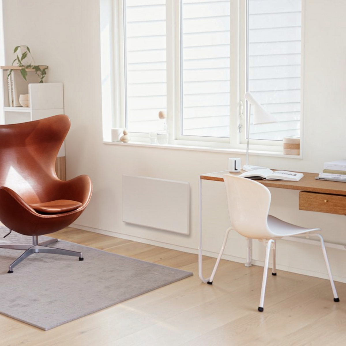 Radiatore elettrico norvegese Klimago™ NOBO TOP bianco installato a parete in un moderno soggiorno luminoso