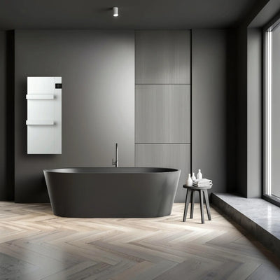 Scaldasalviette elettrico Klimago™ Radialight ONSEN bianco installato in un bagno moderno con vasca scura